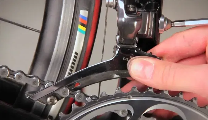 Mechanical Shimano front derailleur beside a bicycle chainring
